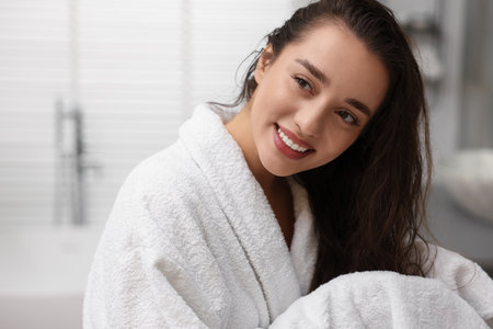 Smiling woman drying hair with towel after shower in bathroomの写真素材