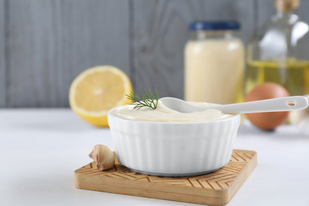 Fresh mayonnaise sauce in bowl and ingredients on white tableの写真素材