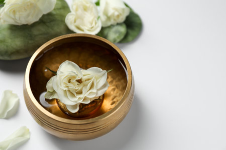 Tibetan singing bowl with water and beautiful rose flowers on white background, space for textの写真素材