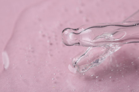 Pipettes with cosmetic serum on pink background, closeup. Space for text