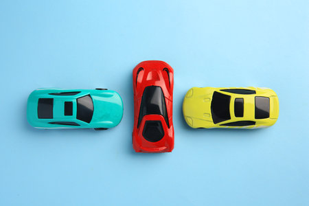 Different bright cars on light blue background, flat lay. Children's toys