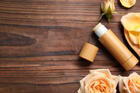 Lip balm and roses on wooden background, flat lay. Space for textの写真素材