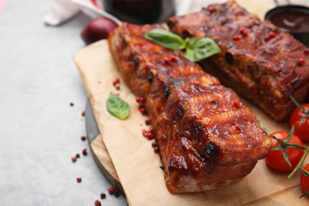 Tasty roasted pork ribs served with basil on gray table, closeup. Space for textの写真素材