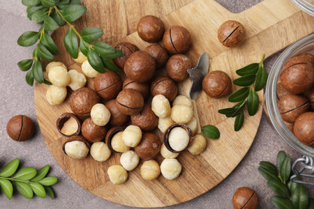 Tasty Macadamia nuts and green twigs on gray table, flat layの写真素材