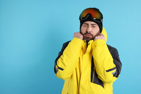Winter sports. Man in ski suit and goggles on light blue background, space for textの写真素材