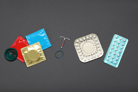 Contraceptive pills, condoms and intrauterine device on gray background, flat lay. Different birth control methodsの写真素材
