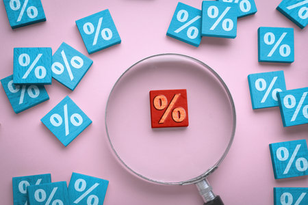 Best mortgage interest rate. Red wooden square with percent sign among light blue ones on pink...