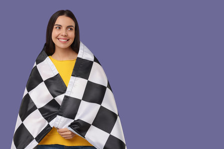 Happy young woman with checkered flag on violet background, space for textの写真素材