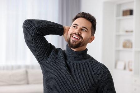 Happy man in stylish sweater at homeの写真素材