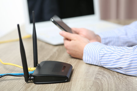 Woman with smartphone connecting to internet via Wi-Fi router at wooden table indoors, closeupの写真素材