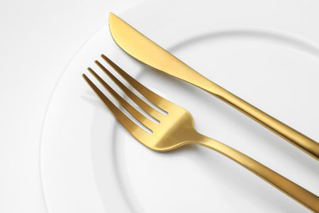 Clean plate, fork and knife on white background, closeupの写真素材