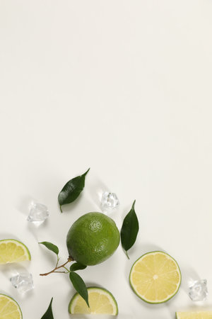 Limes, ice and green leaves on white background, flat lay. Space for textの写真素材