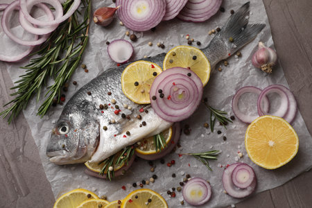 Raw dorado fish with spices, lemon and onion on gray textured table, top viewの写真素材
