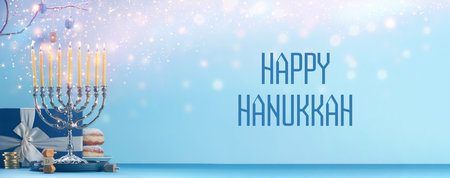Happy Hanukkah. Menorah, donuts, dreidels and gift on blue table, banner designの写真素材