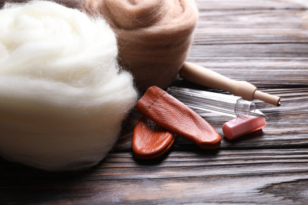Colorful felting wool, finger protectors and needles on wooden table, closeupの写真素材