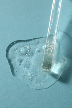 Pipette with cosmetic serum on light blue background, above viewの写真素材