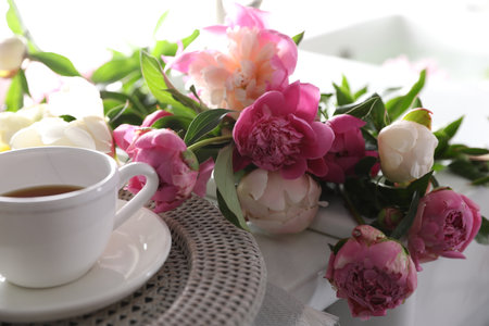 Beautiful peonies and cup of tea on table, closeupの写真素材