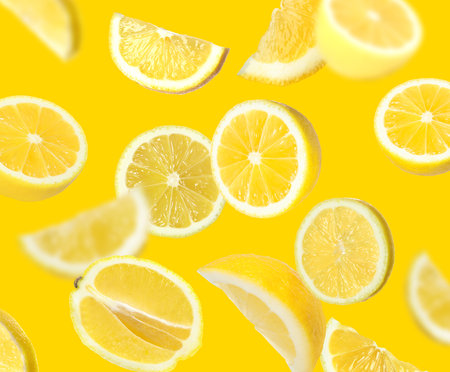 Fresh juicy lemons falling on golden backgroundの写真素材