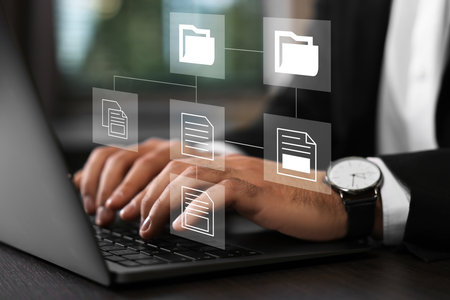 File system. Businessman using laptop at table, closeup. Scheme with folders and documents over computerの写真素材