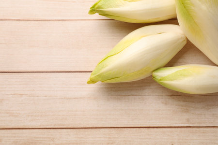 Raw ripe chicories on wooden table, top view. Space for text