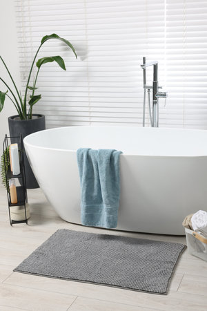 Stylish bathroom interior with bath tub, houseplant and soft light gray matの写真素材