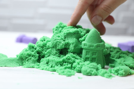 Woman playing with green kinetic sand at white table, closeupの写真素材