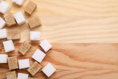 White and brown sugar cubes on wooden table, flat lay. Space for textの写真素材