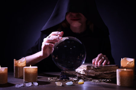 Soothsayer using crystal ball to predict the future at table in darkness. Fortune telling