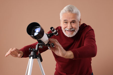 Senior astronomer with telescope on brown backgroundの写真素材