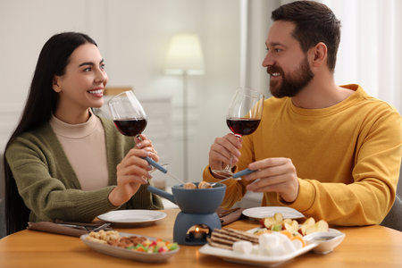 Affectionate couple enjoying chocolate fondue during romantic date at homeの写真素材