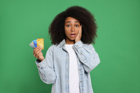Confused woman with credit cards on green background. Debt problemの写真素材