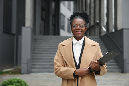 Happy woman with clipboard outdoors, space for text. Lawyer, businesswoman, accountant or managerの写真素材