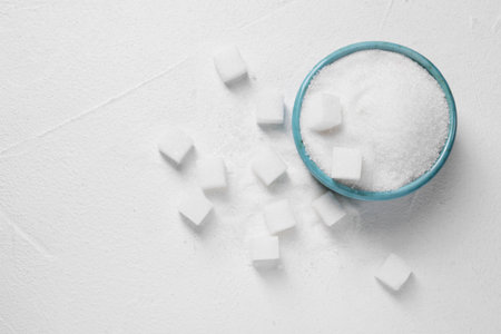 Different types of sugar in bowl on white table, flat lay. Space for textの写真素材