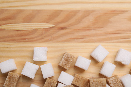 White and brown sugar cubes on wooden table, flat lay. Space for textの写真素材