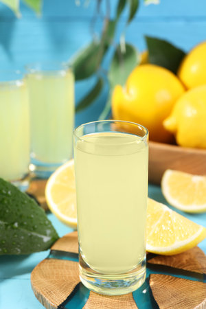 Tasty limoncello liqueur and lemons on light blue table, closeupの写真素材
