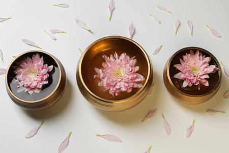 Tibetan singing bowls with water and beautiful chrysanthemum flowers on white background, above viewの写真素材