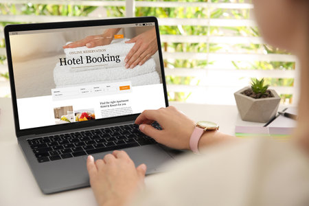Woman using laptop to book hotel at white wooden table, closeupの写真素材
