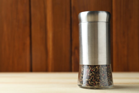 Pepper shaker on light wooden table, closeup. Space for textの写真素材
