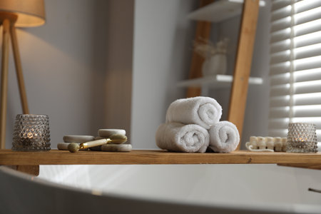 Wooden tray with spa products and burning candles on bath tub in bathroomの写真素材