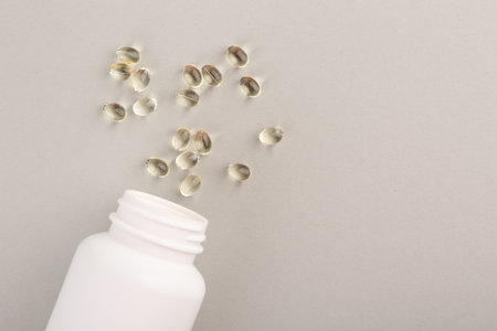 Bottle and vitamin capsules on light gray background, top view. Space for textの写真素材