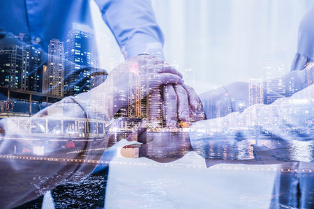 Partnership, cooperation, collaboration. Double exposure of night cityscape and people joining hands