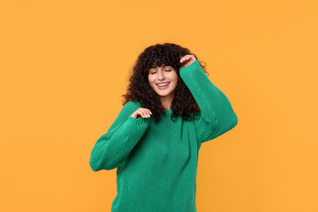 Happy young woman in stylish green sweater on yellow backgroundの写真素材