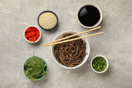 Tasty buckwheat noodles (soba) served on light gray table, flat lay