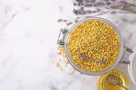 Fresh bee pollen granules, lavender, honey and dipper on light marble table, flat lay. Space for textの写真素材