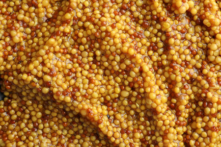 Whole grain mustard as background, top view