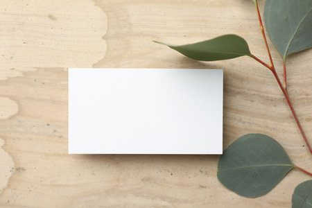 Blank business card and eucalyptus branch on wooden table, flat lay. Mockup for designの写真素材