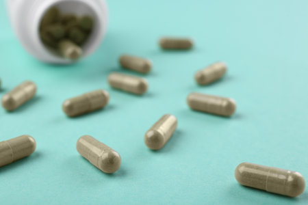 Bottle and vitamin capsules on turquoise background, closeupの写真素材
