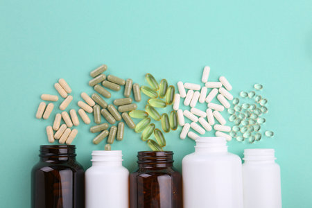 Bottles and different vitamin capsules on turquoise background, flat layの写真素材