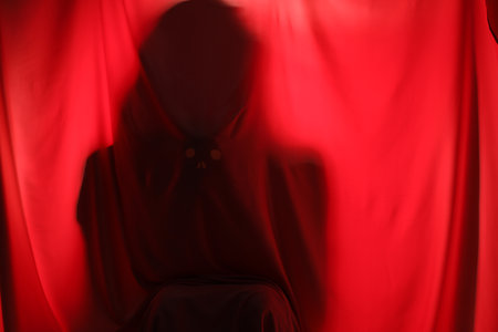 Silhouette of creepy ghost behind red cloth, space for textの写真素材