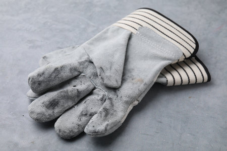 Pair of color gardening gloves on light gray table, closeup
